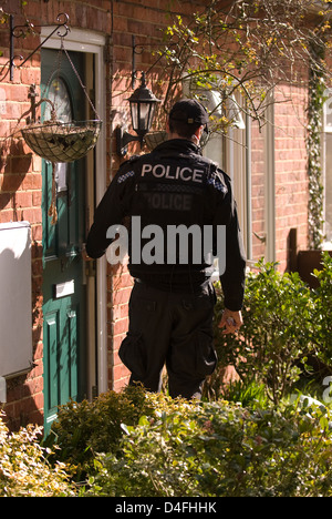 Agent de police entrant dans chambre des suspect arrêté pour menaces de mort, à Selborne, Hampshire, Royaume-Uni. Banque D'Images