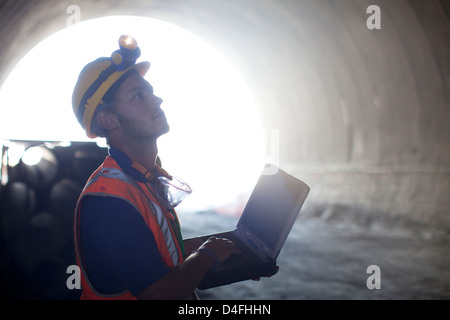 Worker using laptop in tunnel Banque D'Images