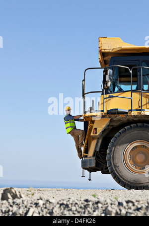 Worker climbing machinery in quarry Banque D'Images