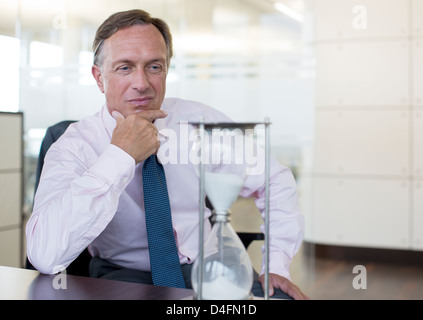 Businessman watching hourglass in office Banque D'Images