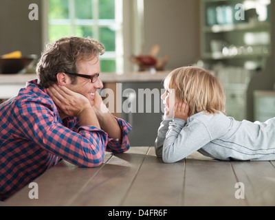 Père et fils en admirant les uns les autres à table Banque D'Images