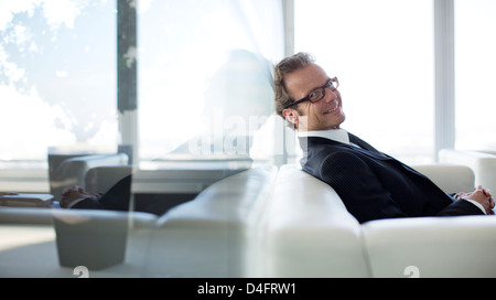 Businessman sitting on sofa in office lobby Banque D'Images