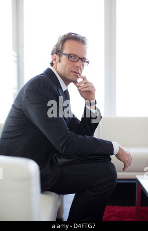 Businessman sitting on sofa in office lobby Banque D'Images