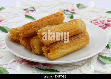 Churros espagnol sur plaque blanche sur serviette fleuri Banque D'Images