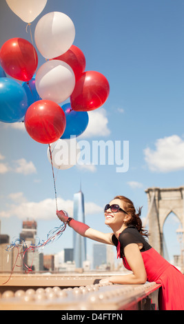 Woman holding bunch of balloons on urban bridge Banque D'Images