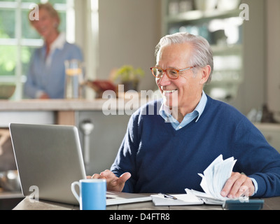 L'homme à l'aide d'ordinateur portable à la table de cuisine Banque D'Images