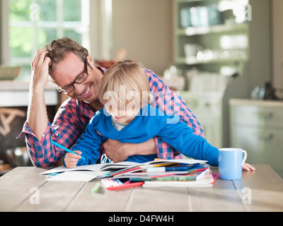 Père et fils à faire des devoirs à table de cuisine Banque D'Images