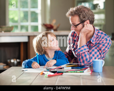 Père et fils à faire des devoirs à table de cuisine Banque D'Images