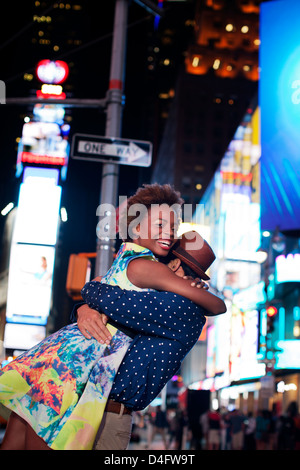 Couple hugging on city street at night Banque D'Images