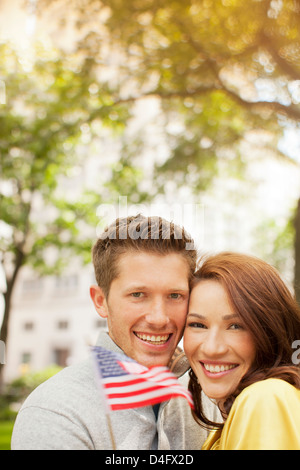 Couple waving American flag in urban park Banque D'Images