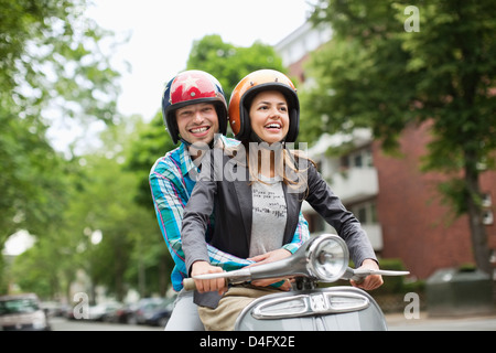 Couple riding scooter together on city street Banque D'Images