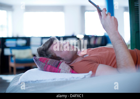 Man using digital tablet on bed Banque D'Images