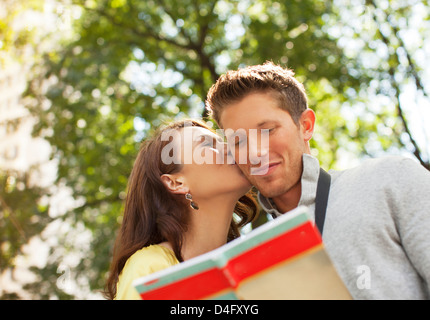 Woman kissing boyfriend in park Banque D'Images