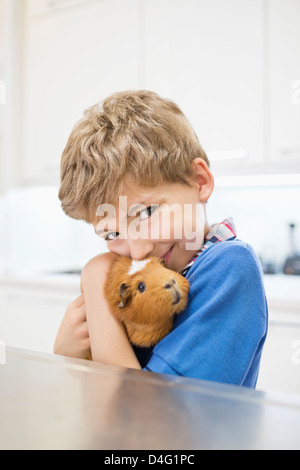 Boy cuddling cobaye dans vet's surgery Banque D'Images