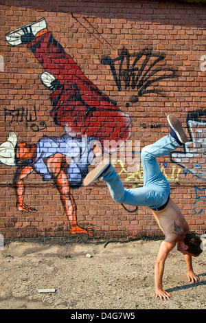 Jeune homme de faire un stand à la main avec un break dancer grafity peint sur l'arrière-plan Banque D'Images
