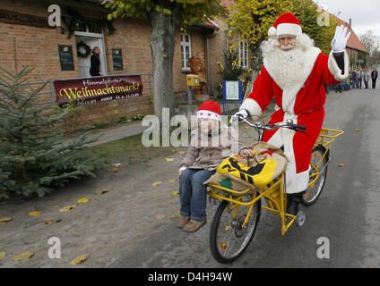 Elisa promenades avec le Père Noël sur son vélo à Flensburg, Allemagne, 10 novembre 2008. Le Père Noël a été accueilli par les enfants de Fuerstenberg et Werder à l'ouverture de la Christman bureau de poste à Flensburg. L'année dernière, 280 000 enfants du monde entier ont écrit des lettres au Père Noël en Himmelpfort. Photo : Bernd Settnik Banque D'Images