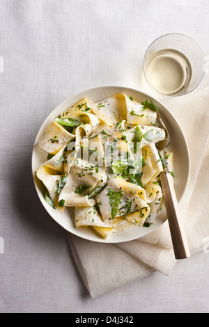 Une assiette de pâtes pappardelle avec ricotta crémeuse, bébés épinards, fines herbes et poivre noir. Banque D'Images