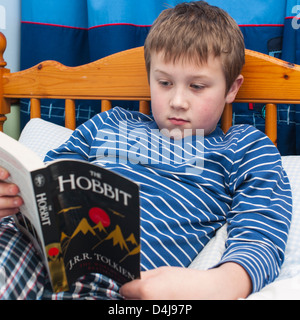 Un garçon de neuf ans, la lecture du livre de Hobbit dans sa chambre à coucher Banque D'Images