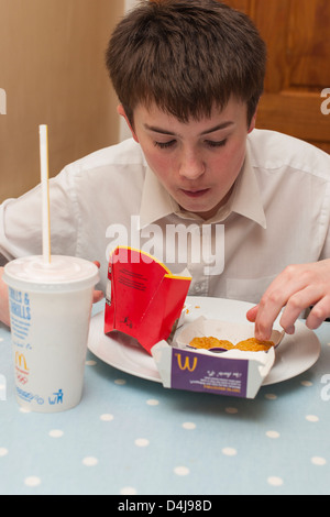 Un garçon de treize ans de manger un repas dans un MCDONALD'S accueil au Royaume-Uni Banque D'Images