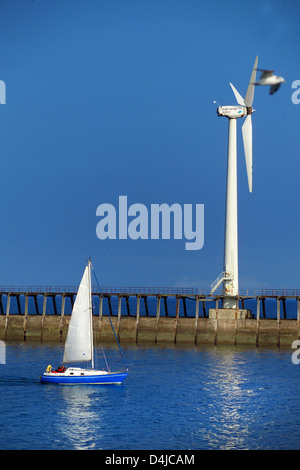 Yacht bleu passant wind turbine, Blyth Harbour, Northumberland Banque D'Images