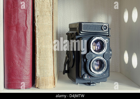 Vintage TLR Appareil photo caméra avec de vieux livres sur le plateau blanc Banque D'Images