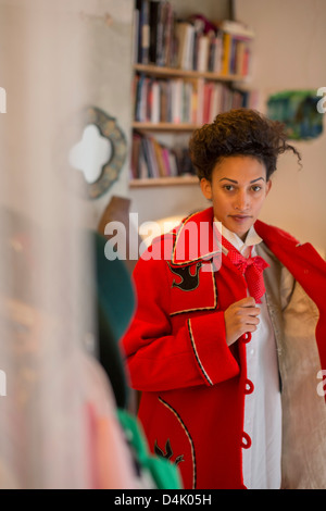 Woman putting on coat Banque D'Images