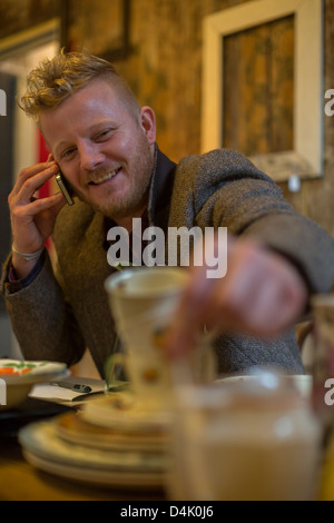 Man talking on cell phone at table Banque D'Images