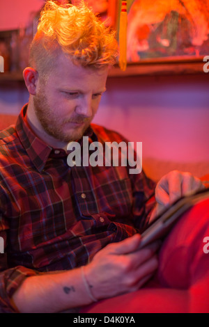 Man using tablet computer on sofa Banque D'Images