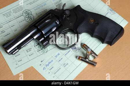 Par un revolver Smith & Wesson et trois cartouches se trouvent sur deux licences de propriété d'armes à Butzbach, près de Francfort, Allemagne, 18 mars 2009. Le .357 Magnum revolver à trois pouces d'un museau est un revolver standart avec viseur fixe. En conséquence de la prise de rampage à Winnenden, politiciens de tous les partis ont appelé à davantage d'attention aux problèmes des enfants Banque D'Images