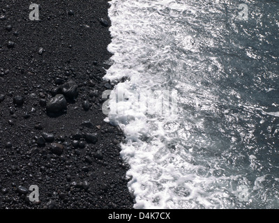 Close-up des vagues s'abattant sur la lave noire du sable et de cailloux à Tenerife Espagne Banque D'Images