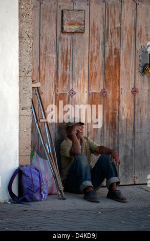 L'homme seul et sans abri dans la rue à Comayagua, Honduras, avec des béquilles et des effets personnels dans un sac en plastique. Banque D'Images