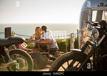 Couple kissing at picnic table outdoors Banque D'Images