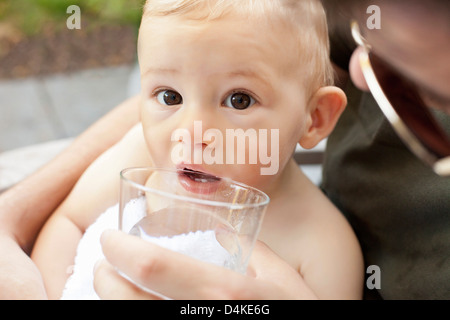 Father helping baby boy verre tasse Banque D'Images