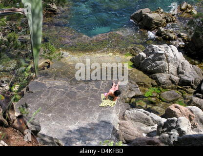 Un touriste se trouve dans le soleil sur la côte rocheuse près de la ville de Calella de Palafrugell sur la Costa Brava, Espagne, 01 juin 2009. Photo : Roland Holschneider Banque D'Images