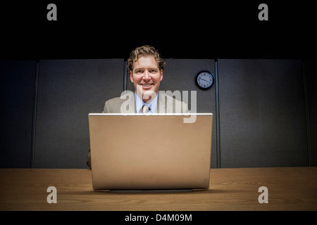 Businessman using laptop in cubicle Banque D'Images