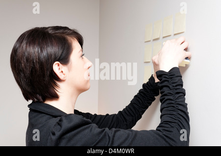 Jeune femme à côté de mur de sticky notes de papier. Banque D'Images