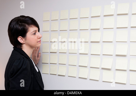 Jeune femme à côté de mur de sticky notes de papier. Banque D'Images