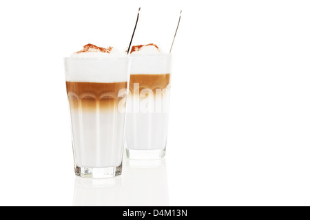 Deux verres latte macchiato avec le chocolat en poudre et des cuillères à l'intérieur sur fond blanc Banque D'Images