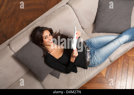 Woman using tablet computer on sofa Banque D'Images