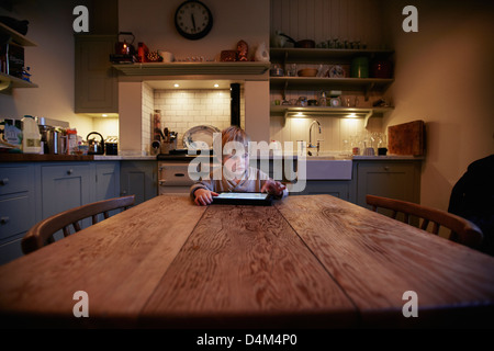 Boy using tablet computer at table Banque D'Images