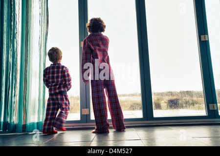 Les garçons en pyjama looking out window Banque D'Images