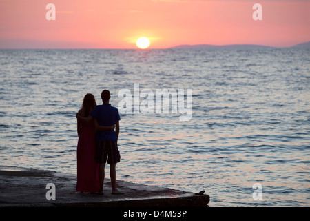 Couple regardant le coucher du soleil sur la jetée Banque D'Images