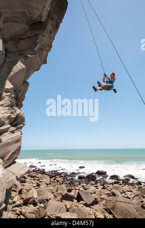 Rock climber abseiling jagged cliff Banque D'Images