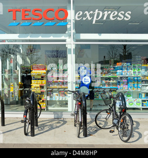 Les places de stationnement pour bicyclettes à l'extérieur fenêtre magasin supermarché Tesco express Banque D'Images