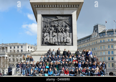 Les enfants en voyage scolaire posant pour grand groupe photo sur socle Colonne Nelsons Banque D'Images