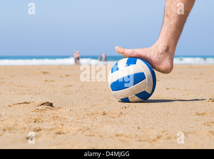 Pied marchant sur une balle sur la plage. Il montre un gros plan et la photo a été prise au niveau du sol Banque D'Images