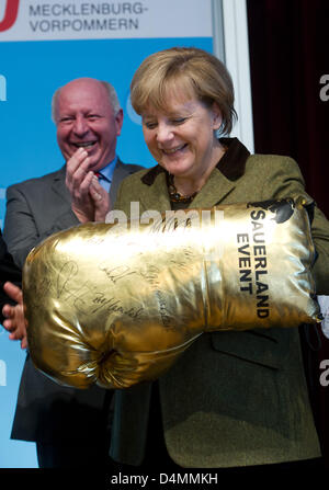 Grimmen, Allemagne. 16 mars 2013. La chancelière allemande, Angela Merkel, est titulaire d'un gant de boxe d'or géant au cours de la réunion les représentants du Parti chrétien démocrate, la CDU en Grimmen, Allemagne, 16 mars 2013. Dans le dos, membre du Bundestag CDU Eckhardt Rehberg (L) est vu. Merkel a été élu à l'unanimité le candidat de tête de Mecklembourg Poméranie CDU. Elle a reçu l'ensemble des 113 voix. Photo : STEFAN SAUER/Alamy Live News Banque D'Images