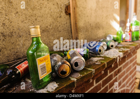 Beaucoup de bouteilles d'alcool et des boîtes sur le foyer d'une chambre très sale. Banque D'Images