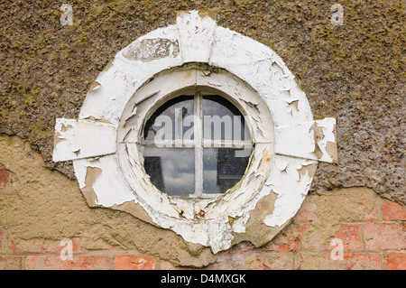 Vieux, fenêtre ronde, sur un mur avec du plâtre cassé Banque D'Images