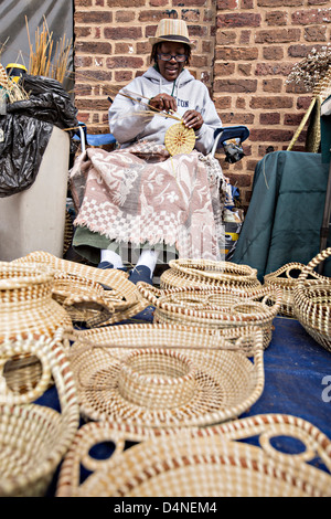 Femme tissant Gullah sweetgrass paniers à l'Historic Charleston City Market sur Market Street à Charleston, SC. Banque D'Images